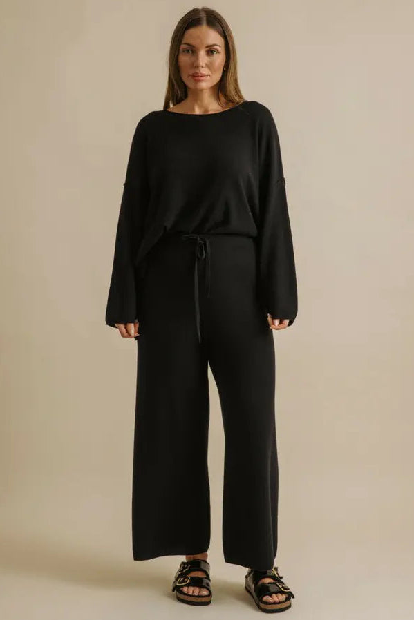 Woman wearing a black outfit on a beige background