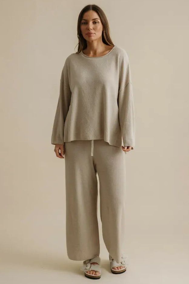 Woman wearing a beige outfit against a plain background