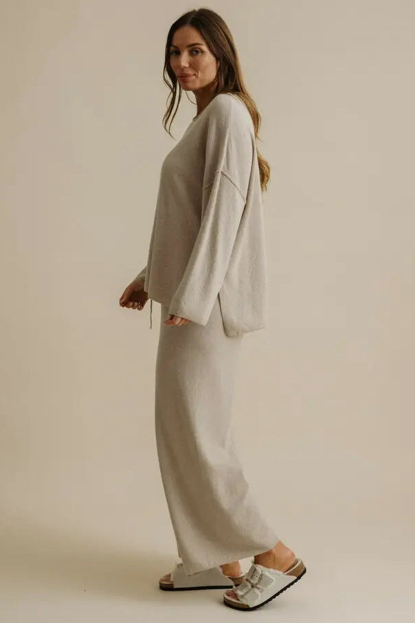 Woman wearing a light gray outfit against a beige background