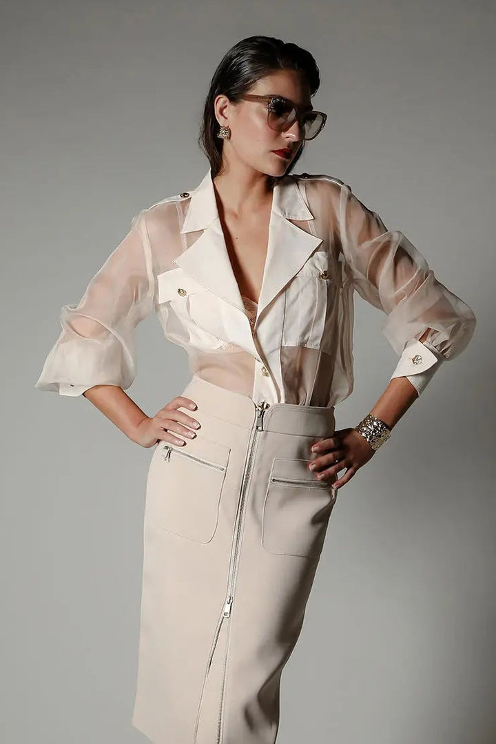 Woman wearing a beige dress with a jacket over a gray background