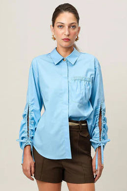 Woman wearing a light blue shirt and brown shorts on a plain background