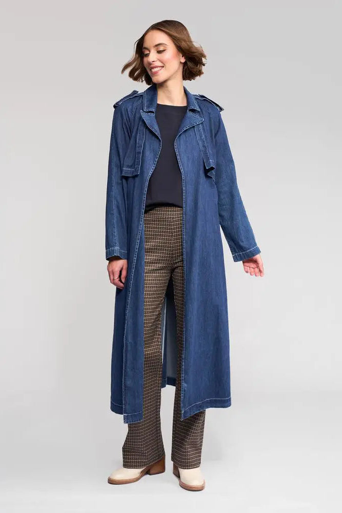 Woman wearing a long blue denim coat on a white background