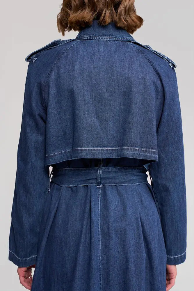 Person wearing a blue denim jacket and skirt set on a plain background