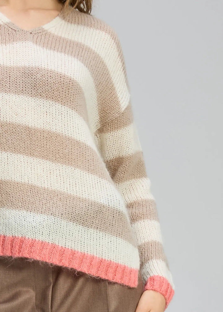 Striped sweater with brown, white, and pink colors on a gray background