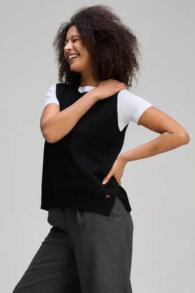 Person wearing a black sleeveless top and gray pants on a plain background. Essential Vest Black