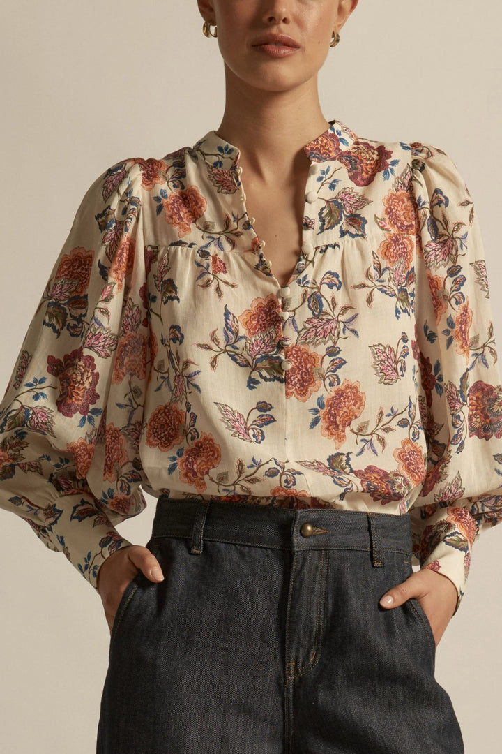 Person wearing a floral blouse with puffed sleeves against a neutral background
