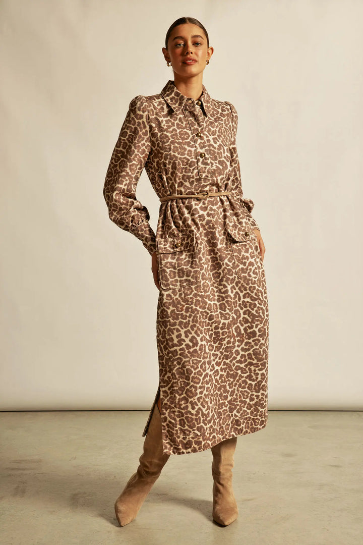 Woman wearing a leopard print dress with a belt against a plain background