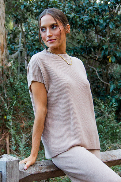 Woman sitting on a wooden fence in a forest setting