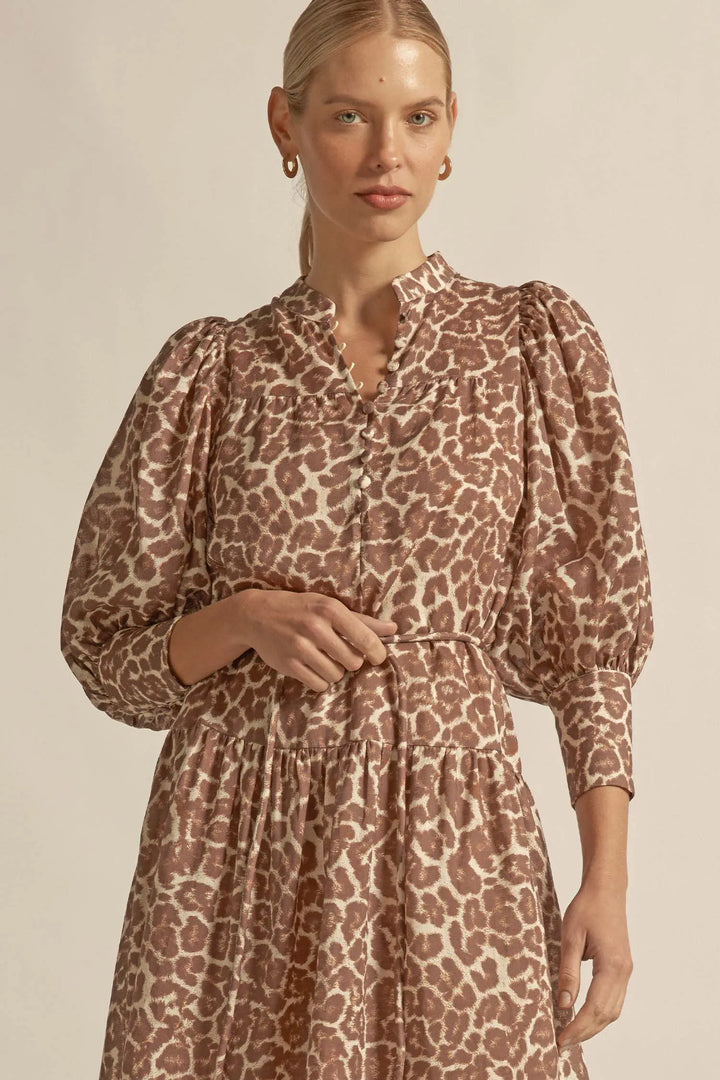 Woman wearing a leopard print dress against a plain background
